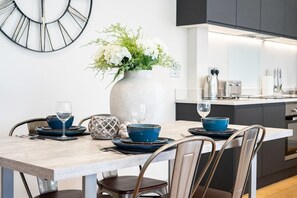 Ein moderner Essbereich mit einem Marmortisch, blauem Geschirr und einer Vase mit weißen Blumen.