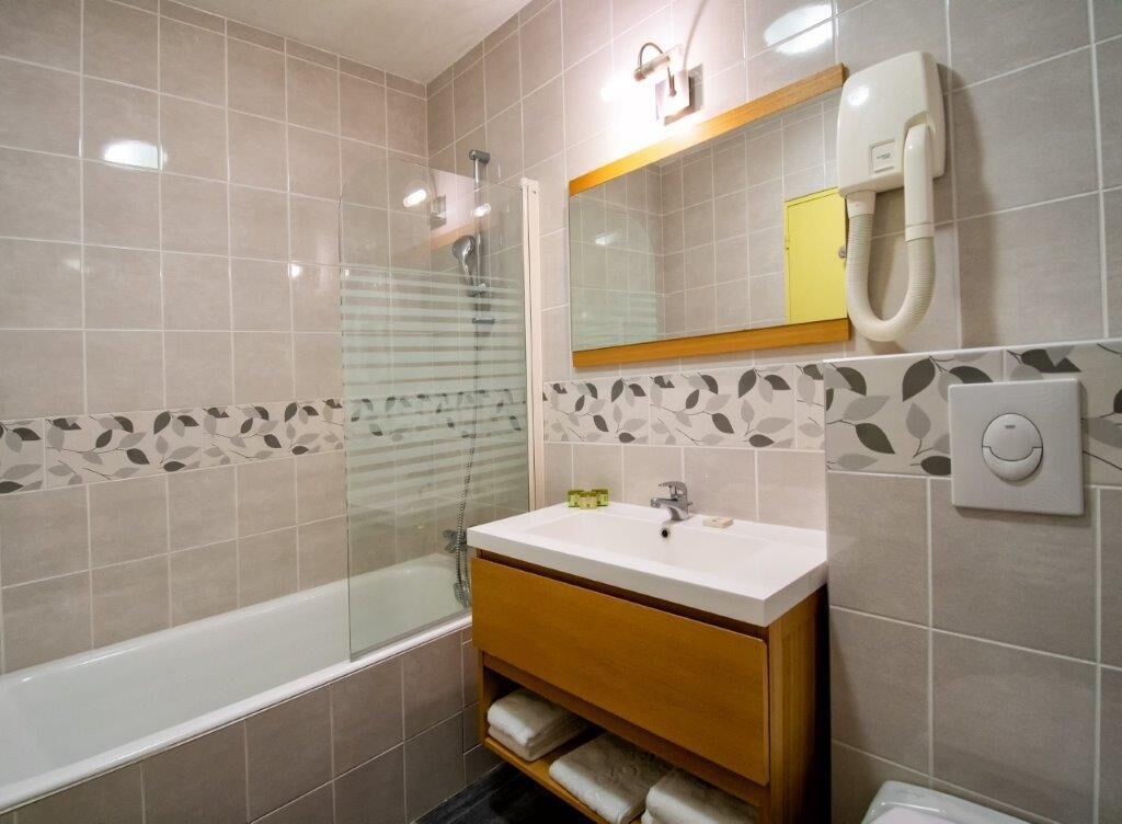 Un baño moderno con bañera, tocador con espejo y retrete.