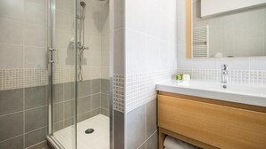 A modern bathroom with a glass-enclosed shower, a white sink with a wooden vanity, and a tiled backsplash. - Logis Hôtel Le Coq Hardi (Pouilly-sur-Loire)