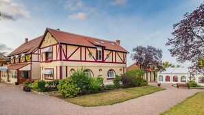 A traditional half-timbered building with a gravel driveway and a small garden area. - Logis Hôtel Le Coq Hardi (Pouilly-sur-Loire)