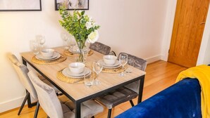Une table à manger dressée avec des bols blancs, des verres à vin et un vase contenant des fleurs blanches.