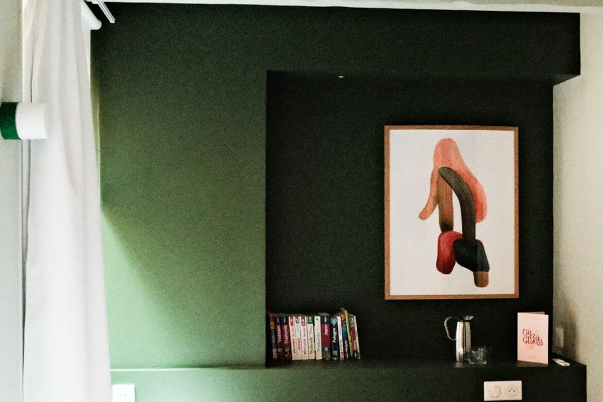 A bedroom with a bed, a bookshelf, a framed picture, and a bedside table.