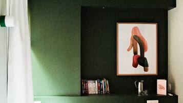 Une chambre à coucher avec un lit, une bibliothèque, un tableau encadré et une table de chevet.