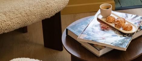 A cozy room with a round wooden table, a magazine, a cup, and a plate of cookies.