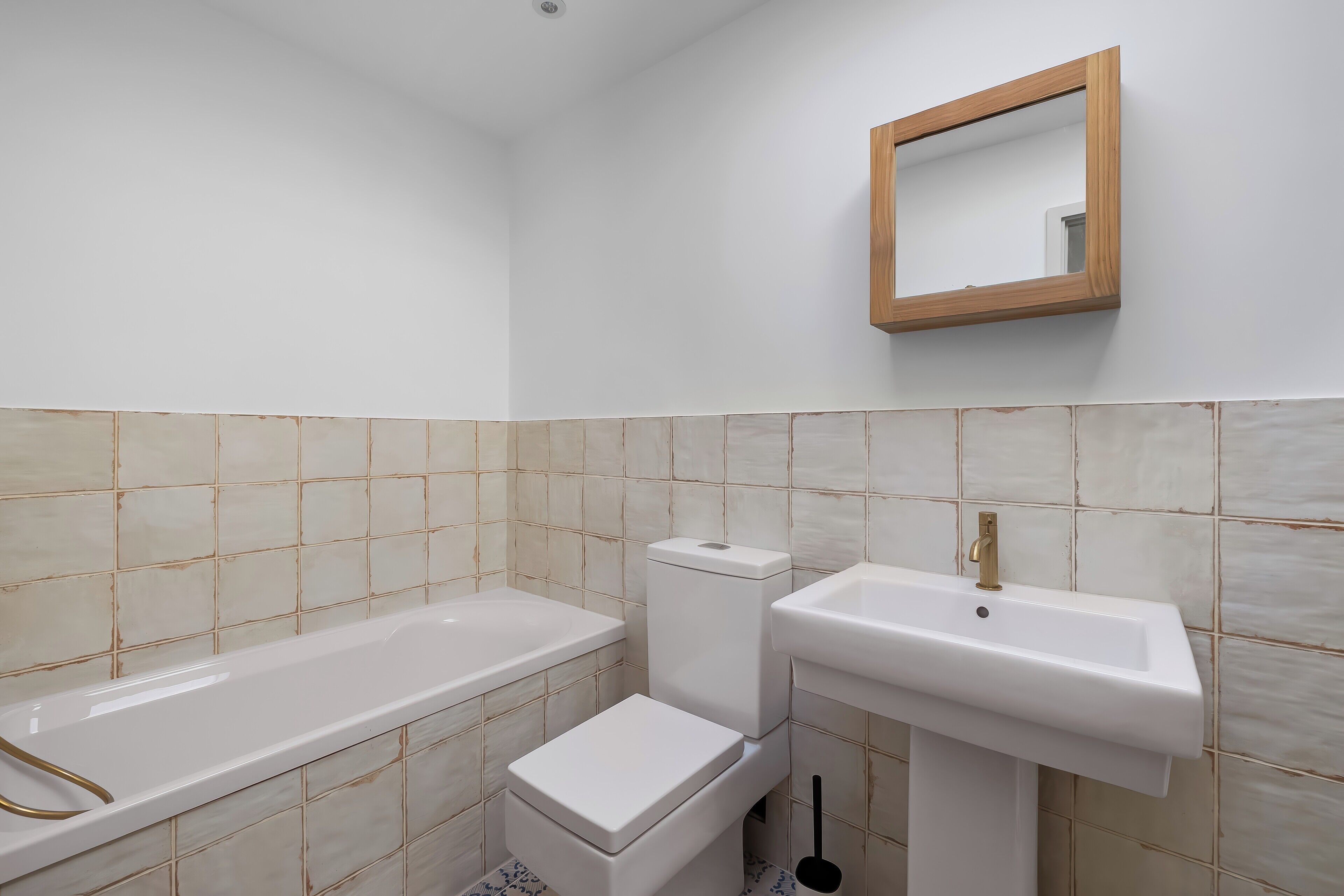 A bathroom with a bathtub, toilet, sink, and a mirror on the wall.