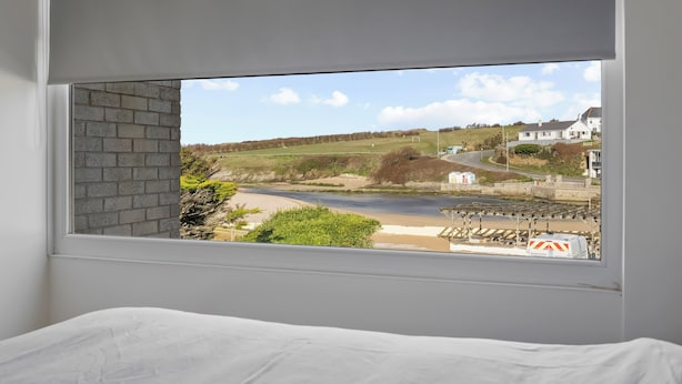 Ein Zimmer mit großem Fenster, Blick auf Strand und Eisenbahnlinie.