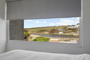 A room with a large window overlooking a beach and a railway track. - 5 Mermaid Court (Newquay)