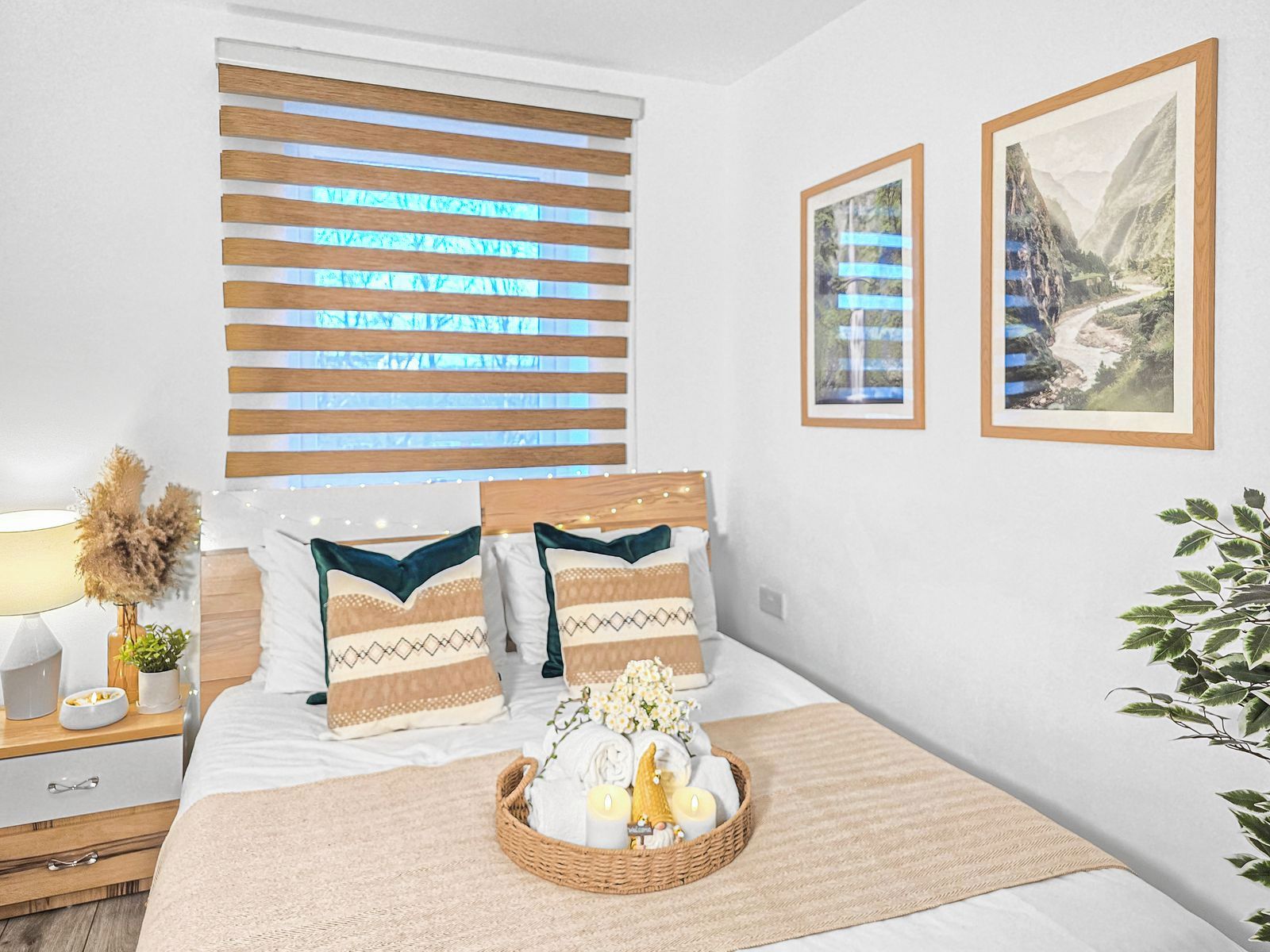 Een keurig opgemaakte slaapkamer met een bed, nachtkastje, lamp en ingelijste foto's aan de muur.