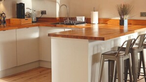A modern kitchen with a wooden countertop, a sink, and bar stools.