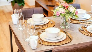 A dining table set with white plates, bowls, and cutlery, accompanied by woven placemats and clear glassware.