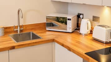 A modern kitchen with a stainless steel sink, a white Russell Hobbs microwave, a kettle, and a toaster.