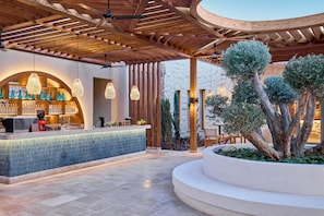 A bar area with a tiled counter, hanging lights, and a stone wall backdrop. - JAZ Viva Almaza Blu, Almaza Bay (Marsa Matrouh)
