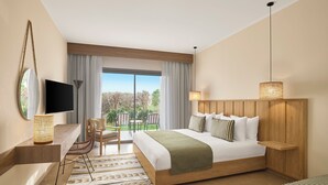 Una habitación de hotel moderna con una cama grande, televisión, escritorio con silla y vistas al exterior.