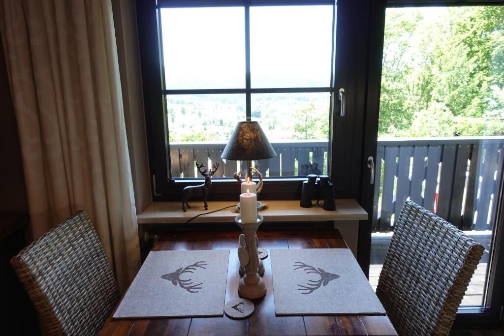 Un comedor con una mesa, dos sillas, un candelabro y vistas por una ventana.