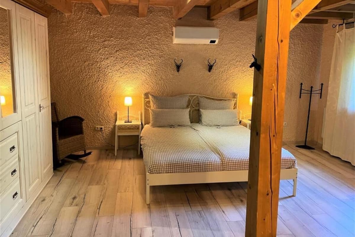 Een slaapkamer met een bed, nachtkastjes, een garderobe en een stenen muur.