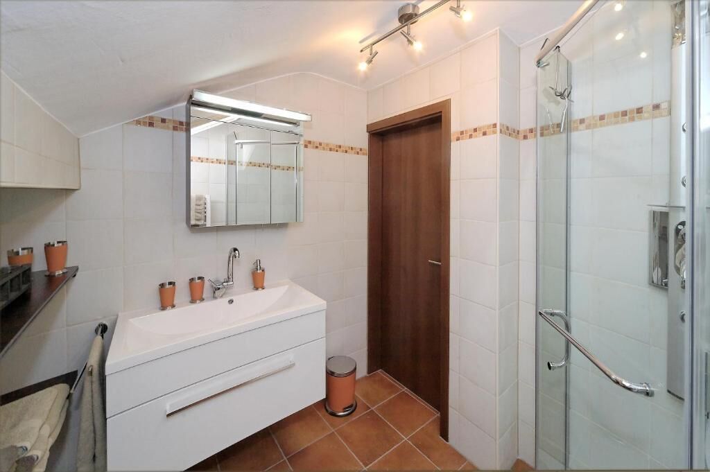 Ein Badezimmer mit Waschbecken, Spiegel und Duschbereich.