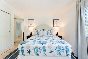 Un dormitorio con una cama, dos lámparas de noche, un cuadro en la pared y una puerta que da a otra habitación.