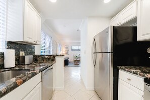 Una cocina moderna con armarios blancos, encimera de granito y electrodomésticos de acero inoxidable.