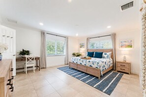 A bedroom with a bed, bedside tables, a desk, and a chair.