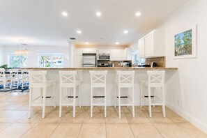 Una cocina moderna con armarios blancos, encimera de granito y taburetes de bar.