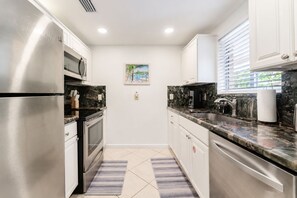 A modern kitchen with stainless steel appliances, granite countertops, and a tiled floor.
