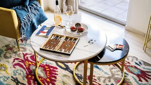 Een ronde tafel met een schaakbord, een fles wijn, een wijnglas en een bord met gebak.