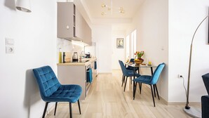 Een moderne keuken met een eethoek, met een centraal kookeiland, blauwe stoelen en een hanglamp.