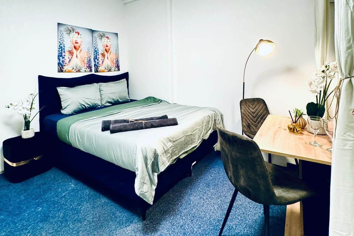 A modern bedroom with a bed, bedside tables, a desk, and a chair.