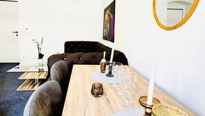 A modern living room with a wooden dining table, grey sofa, and a large mirror. - Spacious 7BR Apartment Prime Location (Vienna)