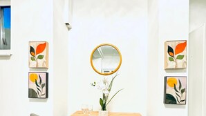 A room with a wooden table, two grey chairs, a round mirror, and three framed artworks on the walls. - Spacious 7BR Apartment Prime Location (Vienna)