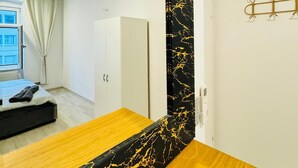 A modern bedroom with a large mirror, a wooden bed, a white wardrobe, and a window with curtains. - Spacious 7BR Apartment Prime Location (Vienna)