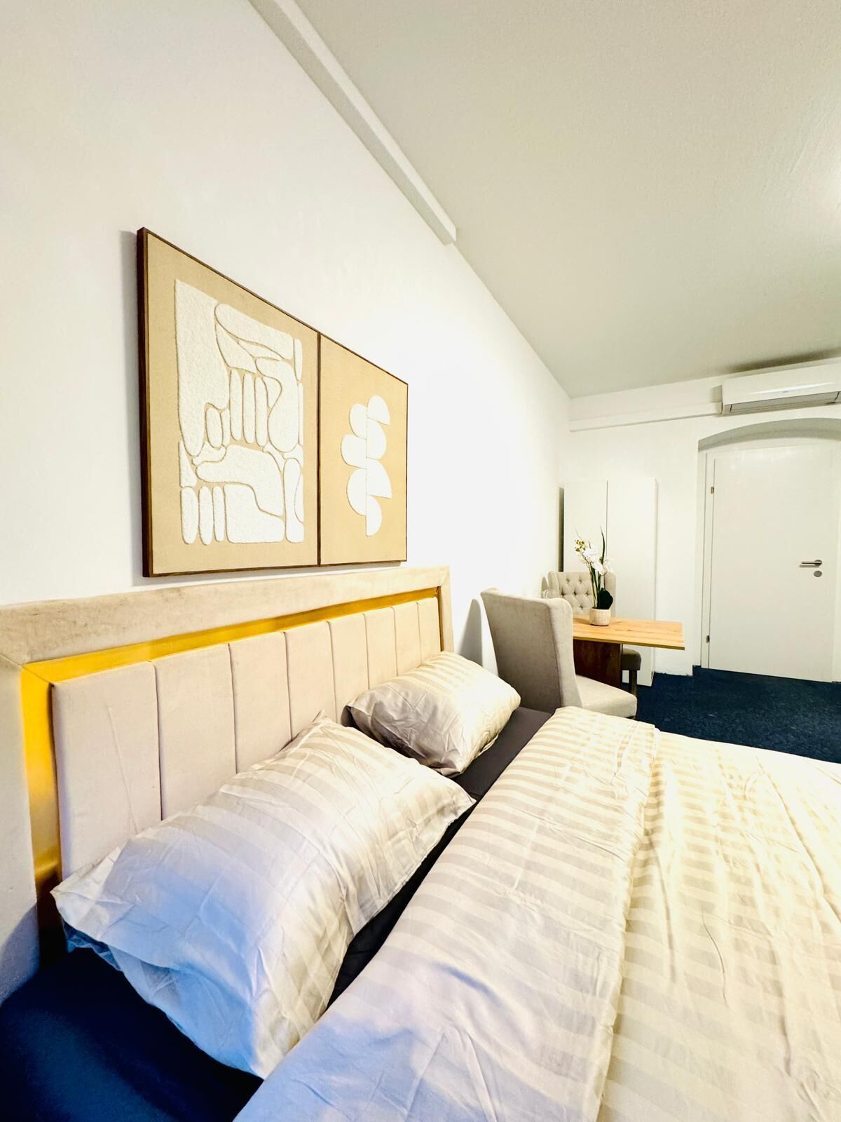 Una camera d'albergo con un letto, una sedia, una scrivania e una porta.