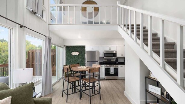 A spacious loft-style apartment with a dining area, kitchen, and a staircase. - D4 Creekside Walk to Convention and The Landing (Branson)