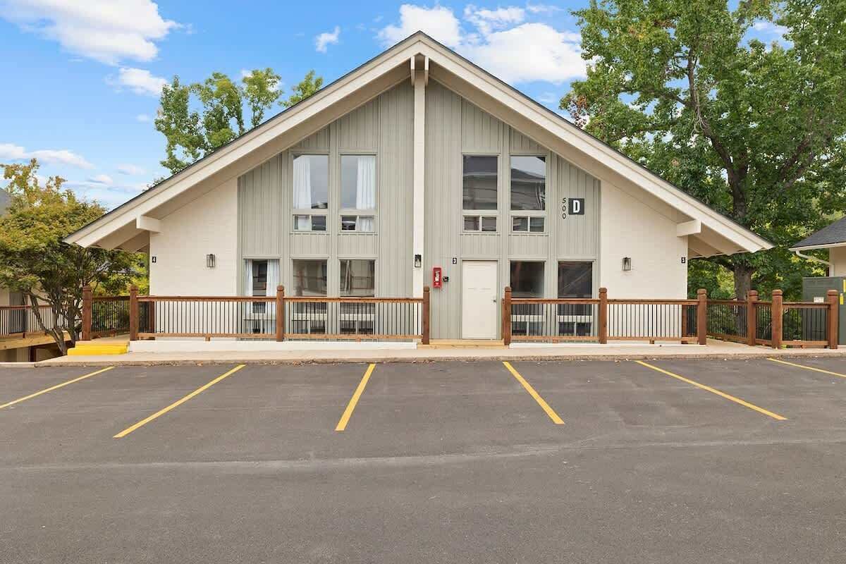 A building with a gabled roof, a gated entrance, and a parking lot with marked spaces.