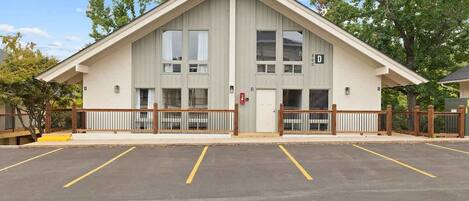 A building with a gabled roof, a gated entrance, and a parking lot with marked spaces.