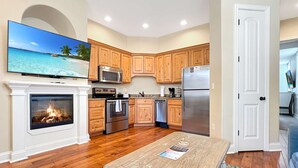 A modern kitchen with wooden cabinets, stainless steel appliances, a fireplace, and a flat-screen TV mounted above it. - L-3 Stunning Views clean cozy close to SDC (Branson)