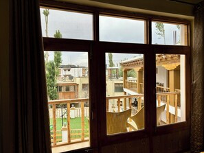 Une pièce dotée d’une grande fenêtre donnant sur une cour intérieure, avec une terrasse en bois et une vue sur les bâtiments voisins.