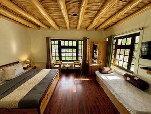 Un dormitorio con cama, escritorio, silla, armario y ventanas amplias.
