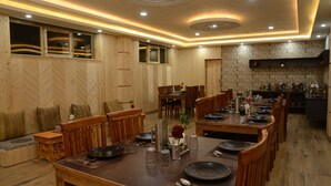 A spacious dining area with wooden furniture, a central table set for a meal, and a kitchen in the background. - City Heart Boutique Stays (Leh)