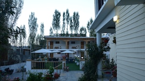 A courtyard with outdoor seating, potted plants, and a building with a balcony. - City Heart Boutique Stays (Leh)