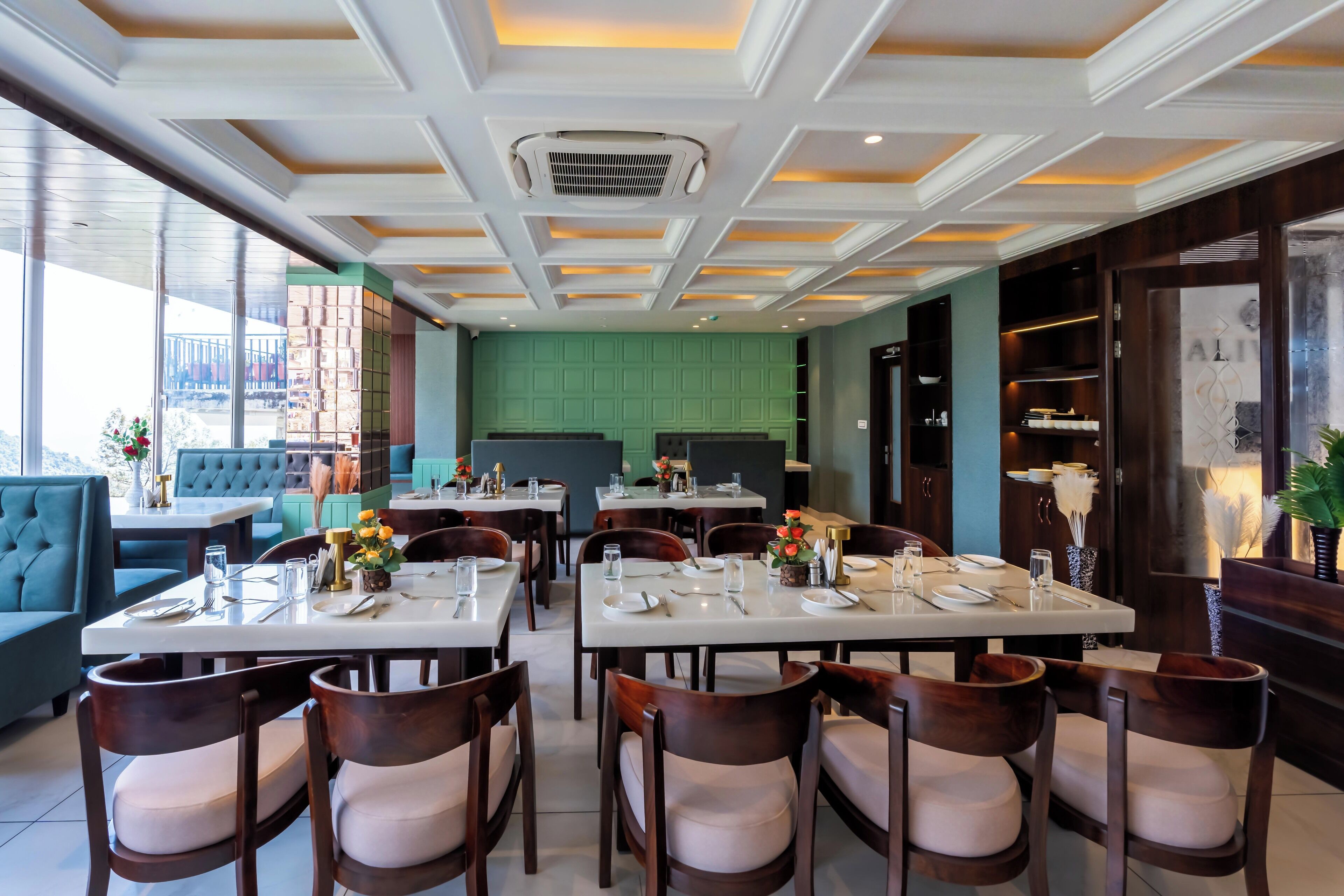 Un ristorante con diversi tavoli e sedie, una parete verde e un soffitto con illuminazione a incasso.