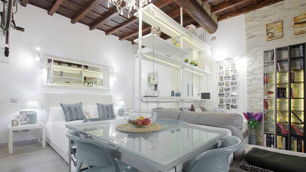 A modern living room with a glass dining table, a sofa, and a bookshelf. - Your nest in Trastevere, the heart of Rome - Your Nest in the Heart of Rome (Roma)