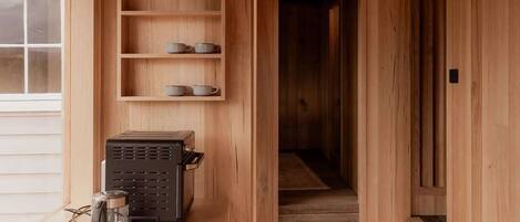 A wooden interior with a kitchenette, a hanging light fixture, and a staircase leading to another room.