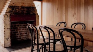 A rustic dining area with a brick oven, wooden walls, and metal chairs. - 'Engineers Hut 1823' in Historic Richmond (Richmond)