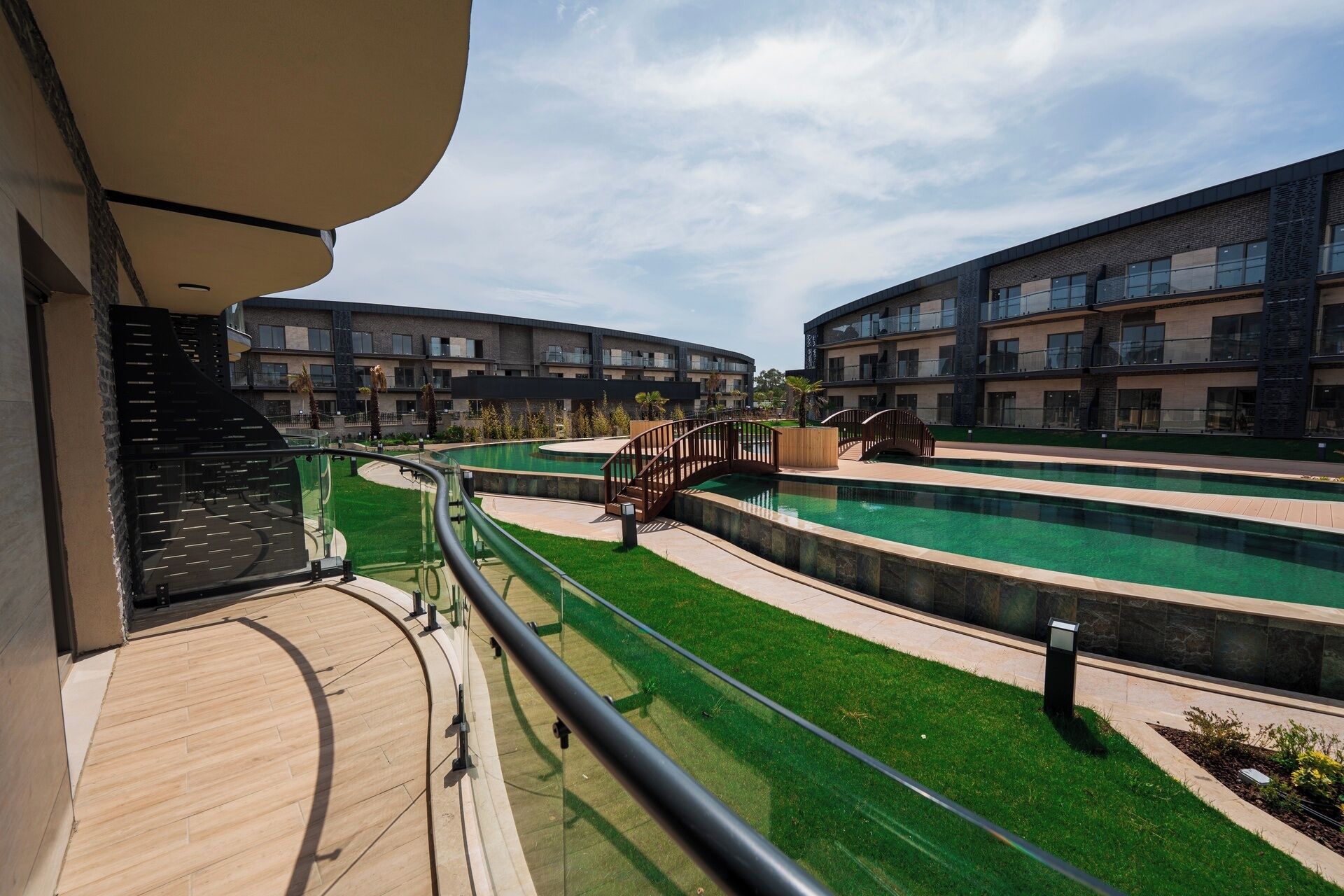 A modern hotel with a pool area, including a bridge and a staircase leading to the upper floors.