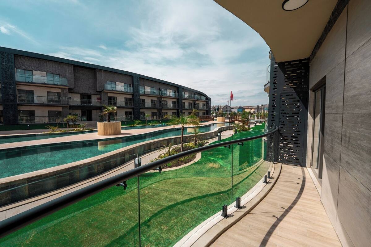 Un hotel moderno con zona de piscina, vistas de los edificios circundantes y un balcón con barandilla de cristal.