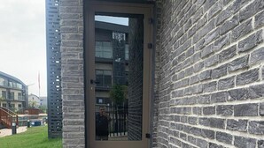 Betonnen traptreden leiden naar een glazen deur van een gebouw met een stenen gevel.