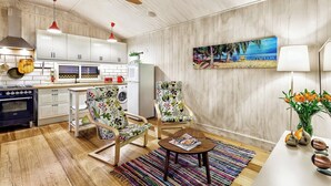 Een moderne keuken met witte kastjes, een houten plafondventilator en een eetgedeelte met twee stoelen en een tafel.