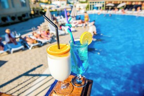 Two drinks on a tray by a poolside with lounge chairs and umbrellas in the background. - TITANIK BAKU (Baku)