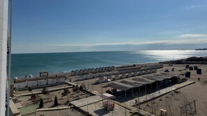 A beachside hotel with multiple beach umbrellas and cabanas, a sandy beach, and a clear view of the ocean. - TITANIK BAKU (Baku)